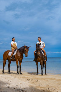 Man and woman riding horse at beach