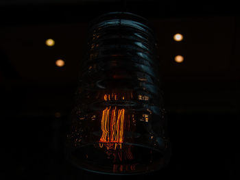 Close-up of illuminated light bulb against black background