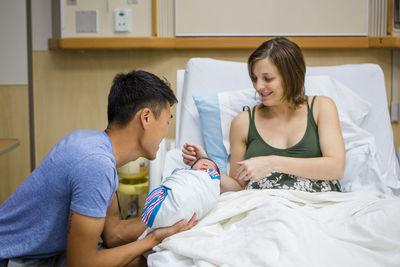 A new mother and father proudly gaze at their newborn daughter