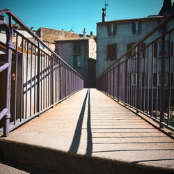 Footbridge leading towards house against sky