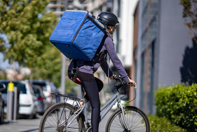 Delivery woman riding electric bicycle in city