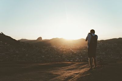 Rear view of man photographing at sunset