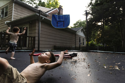 Shirtless brothers playing on trampoline at yard