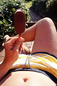 Low section of man holding ice cream bar in yard