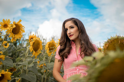 Smiling mid adult woman standing amidst sunflowers on farm