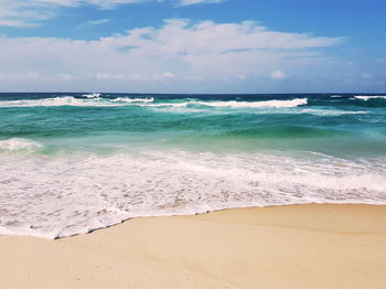 Scenic view of beach against cloudy sky