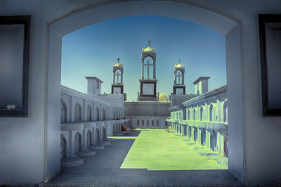Buildings against clear blue sky seen through colonnade
