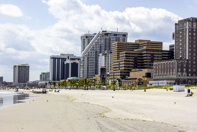 Boardwalk buildings in city against sand and sky
