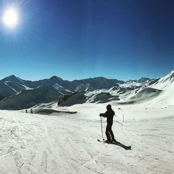 Person skiing on snow field against blue sky