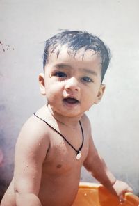 Portrait of shirtless wet baby boy standing in bucket