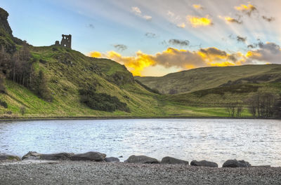 Scenic view of river by mountains against sky
