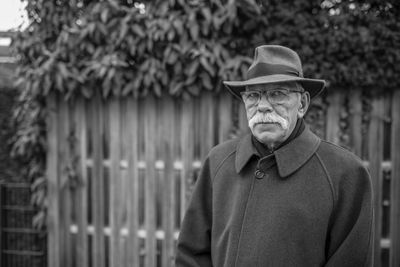 Portrait of man wearing hat standing against trees