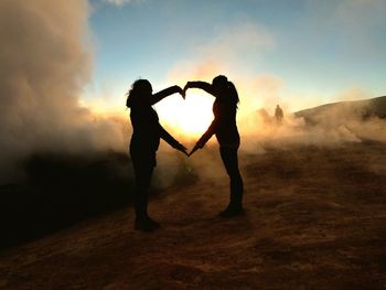 Silhouette of woman against cloudy sky at sunset