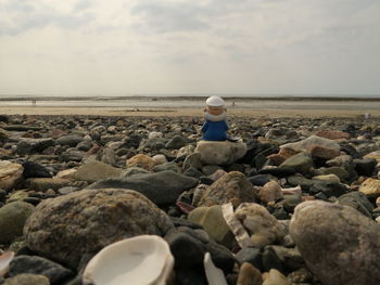 Rear view of person in costume sitting at beach against sky