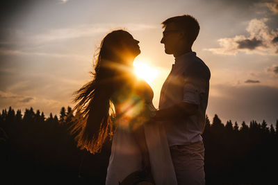 Couple standing against sky during sunset