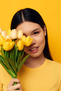 Close-up of young woman holding yellow flowers