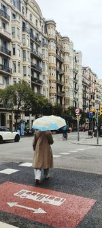 Rear view of man walking on street in rain