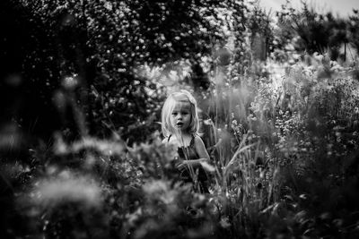 Portrait of girl standing amidst plants