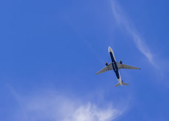 Low angle view of airplane flying against blue sky