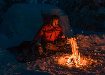 Man sitting by bonfire at night