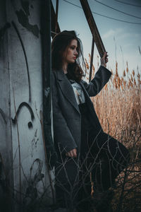 Young woman standing by old wall