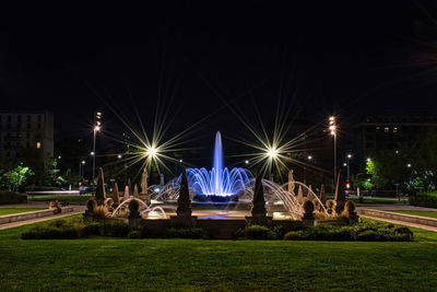 Illuminated park in city against sky at night