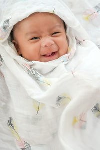 Portrait of cute baby girl lying on bed