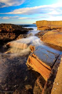 Scenic view of rocks on shore against sky