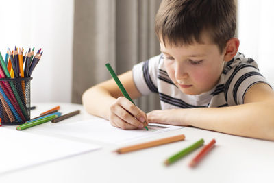 Boy drawing on book at table