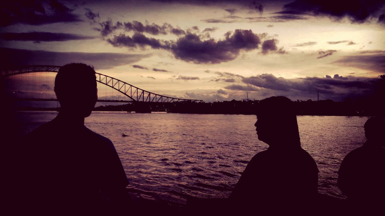 SILHOUETTE MAN LOOKING AT SUSPENSION BRIDGE AGAINST SKY