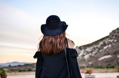 Rear view of woman with hat standing against sky
