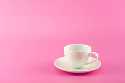 Close-up of coffee cup against pink background