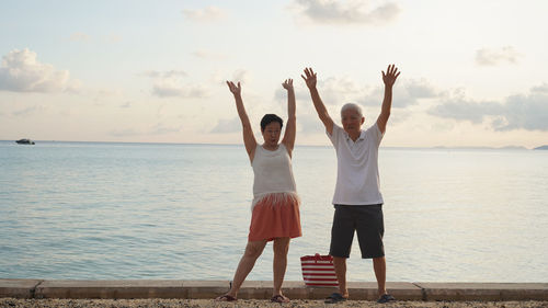 Friends standing by sea against sky