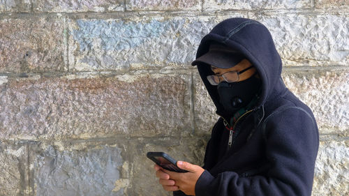 Midsection of man using mobile phone against wall