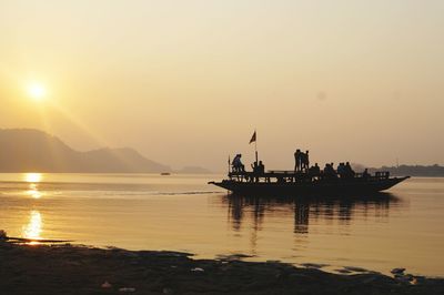 Silhouette of people on boat at beach during sunset