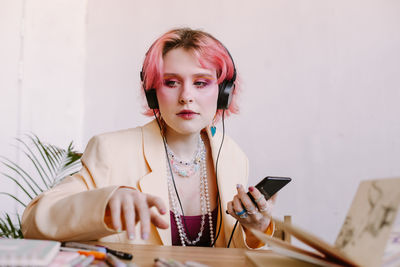 Creative young woman using smartphone , listen to music at table with scetchbook and painting 