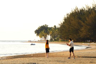 People on beach against clear sky