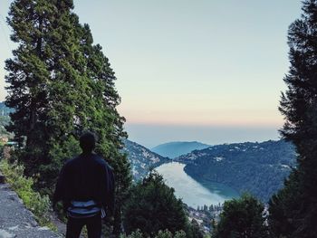 Rear view of man looking at mountains against sky
