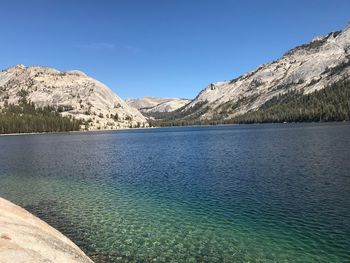 Scenic view of lake and mountains against clear blue sky