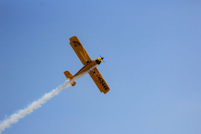 Low angle view of airplane flying against clear blue sky