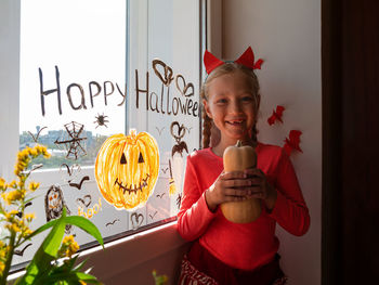 Child painting pumpkin window preparing celebrate halloween kid draws decorates room with paper bats