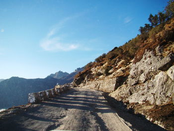 Footpath leading towards mountain against blue sky