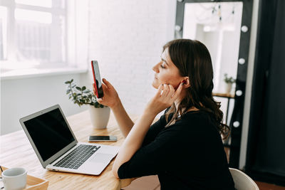 Business girl freelancer in casual clothes works using wireless technology in the home office