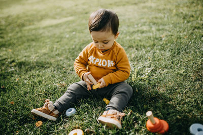 Full length of boy sitting on field