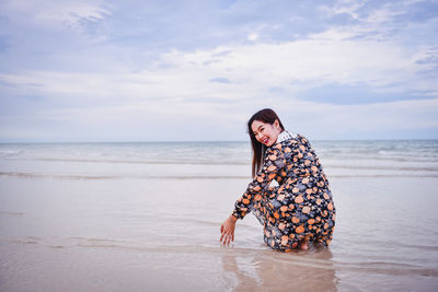 Young woman on beach against sky