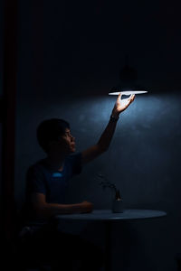 Young man touching illuminated light bulb