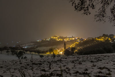 Illuminated snow covered land against sky at night