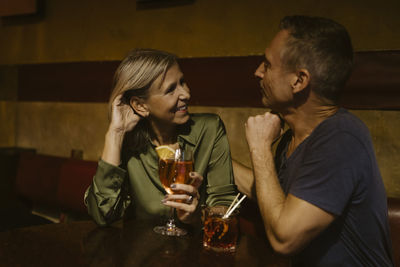 Man talking with woman holding wineglass while sitting at restaurant