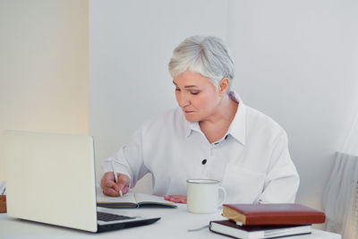 Portrait of young woman using mobile phone while sitting on table