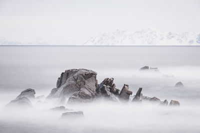 Sea ringed by snowy rocks and distant mountains